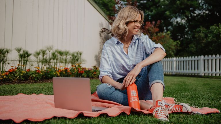 Une femme assise dans un parc avec son ordinateur portable